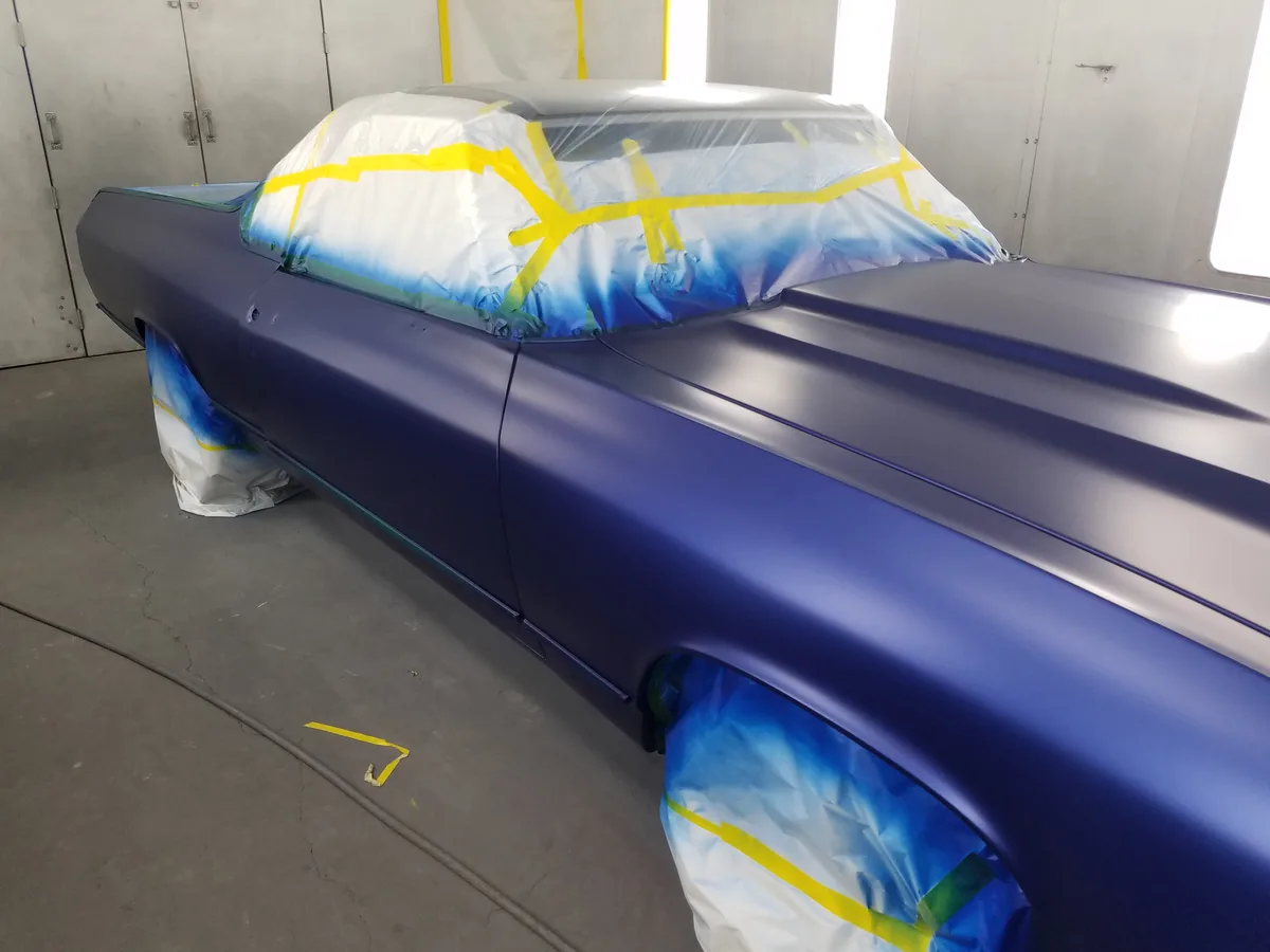 Classic car with racing stripes in paint booth during refinishing