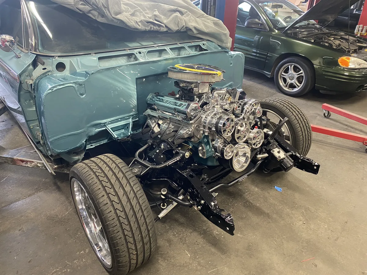 Teal vintage car with exposed engine on display stand