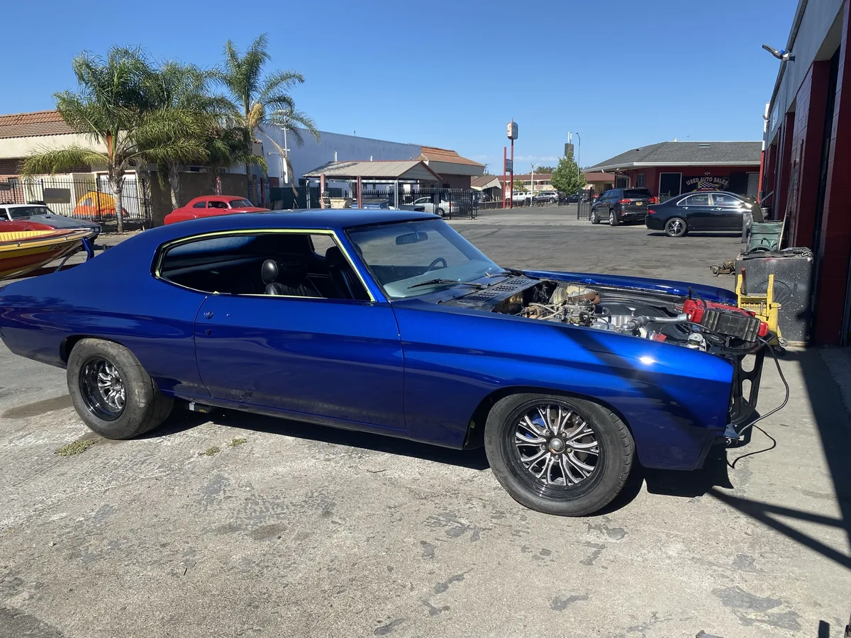 Blue classic sedan with chrome engine at outdoor car show